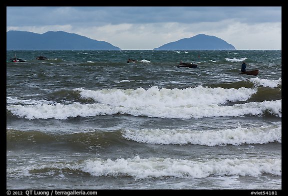 Man rowing coracle boat in distance amidst large waves. Da Nang, Vietnam