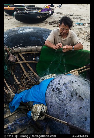 Fisherman repairing net on beach. Da Nang, Vietnam