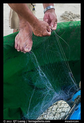Close-up of hands and feet of man mending net. Da Nang, Vietnam (color)