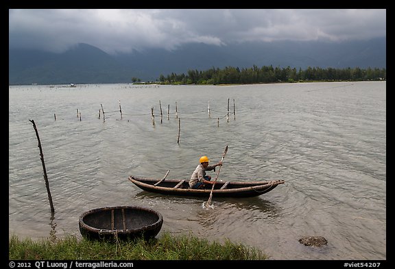 Fisherman rowing canoe in lagoon. Vietnam (color)