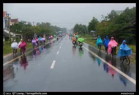 Riders wearing colorful ponchos on wet road on Hwy 1 south of Hue. Vietnam (color)