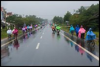 Riders wearing colorful ponchos on wet road on Hwy 1 south of Hue. Vietnam (color)