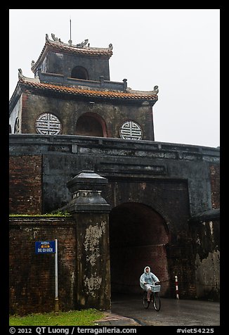 Biking through citadel gated entrance in the rain. Hue, Vietnam (color)