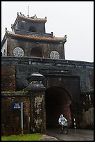 Biking through citadel gated entrance in the rain. Hue, Vietnam (color)