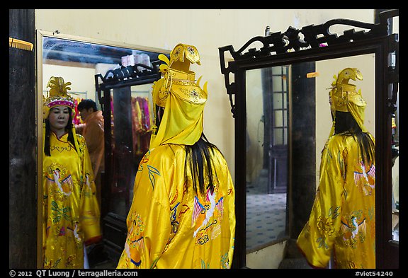 Woman in imperial dress checking herself in mirror, citadel. Hue, Vietnam