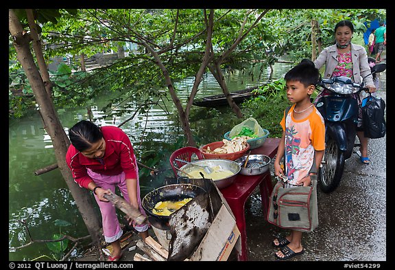 Boy waiting for donut coooked near canal, Thanh Toan. Hue, Vietnam