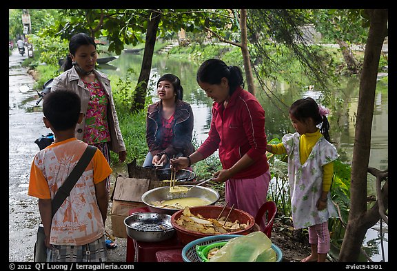 Woman preparing donuts near canal. Hue, Vietnam (color)