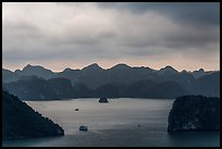 Boat amongst islands under dark sky. Halong Bay, Vietnam (color)