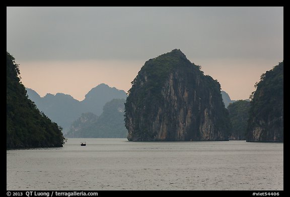 Fishing boat dwarfed by limestone islands. Halong Bay, Vietnam (color)