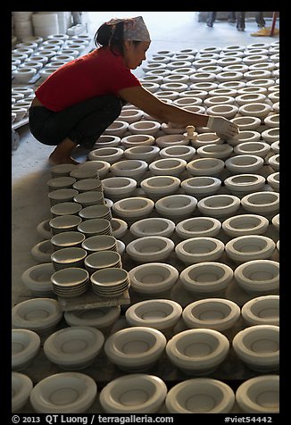 Woman laying ceramic bowls to dry in workshop. Bat Trang, Vietnam (color)