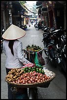 Woman pushing bicycle loaded with vegetable for sale in narrow street, old quarter. Hanoi, Vietnam (color)