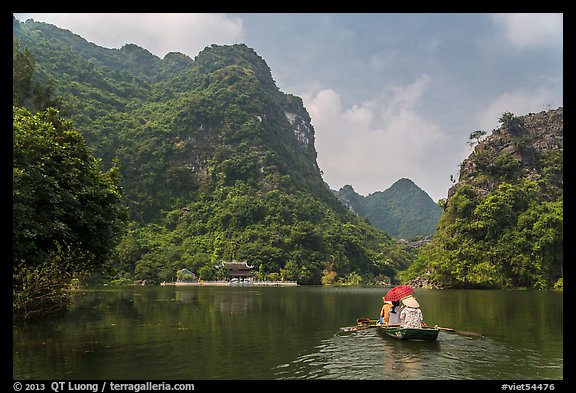 Boat journeying below tall lush cliffs, Trang An. Ninh Binh,  Vietnam (color)