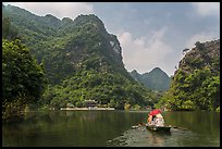 Boat journeying below tall lush cliffs, Trang An. Ninh Binh,  Vietnam ( color)