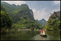 Boat journeying below tall lush cliffs, Trang An. Ninh Binh,  Vietnam ( color)