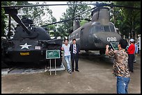 Tourists pose with tanks and helicopters, War Remnants Museum, district 3. Ho Chi Minh City, Vietnam (color)