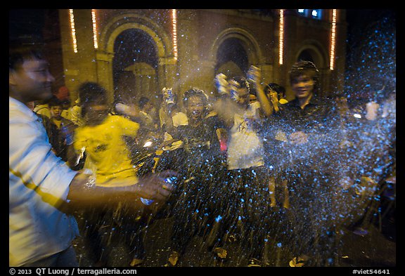 Revellers celebrating with spray in front of Notre Dame Cathedral on Christmas Eve. Ho Chi Minh City, Vietnam (color)