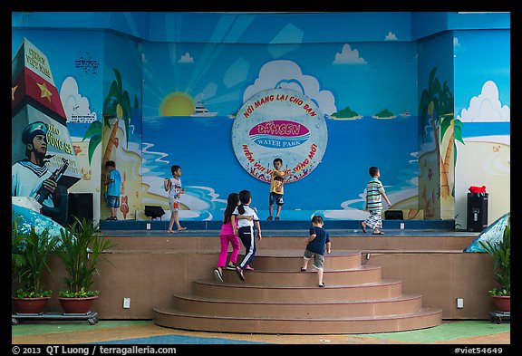 Children on stage next to militaristic mural, Dam Sen Water Park, district 11. Ho Chi Minh City, Vietnam (color)