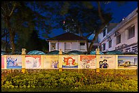 Fenced buildings with propaganda posters at night. Ho Chi Minh City, Vietnam