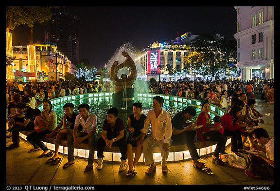 People sitting on fountain at night, New Year eve. Ho Chi Minh City, Vietnam (color)