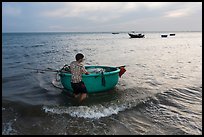 Man holding coracle boat. Mui Ne, Vietnam (color)