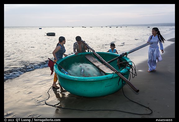 Family around their coracle boat. Mui Ne, Vietnam