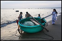 Family around their coracle boat. Mui Ne, Vietnam (color)