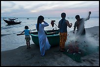 Fishermen folding net out of coracle boat as children watch. Mui Ne, Vietnam ( color)