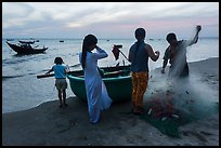 Fishermen folding net out of coracle boat as children watch. Mui Ne, Vietnam (color)