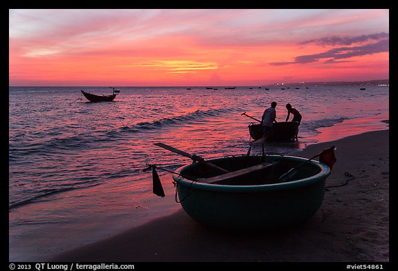 Fishermen bringing round coracle boat to shore at sunset. Mui Ne, Vietnam (color)