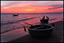 Fishermen bringing round coracle boat to shore at sunset. Mui Ne, Vietnam ( color)