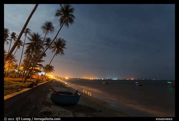 Beach, palm trees and coracle boats at night. Mui Ne, Vietnam