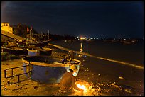 Man with fire next to coracle boat at night. Mui Ne, Vietnam (color)