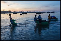 Fishermen using coracle boats to transport cargo at dawn. Mui Ne, Vietnam (color)