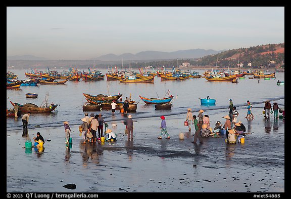 Hawkers gather on mirror-like beach in early morning. Mui Ne, Vietnam
