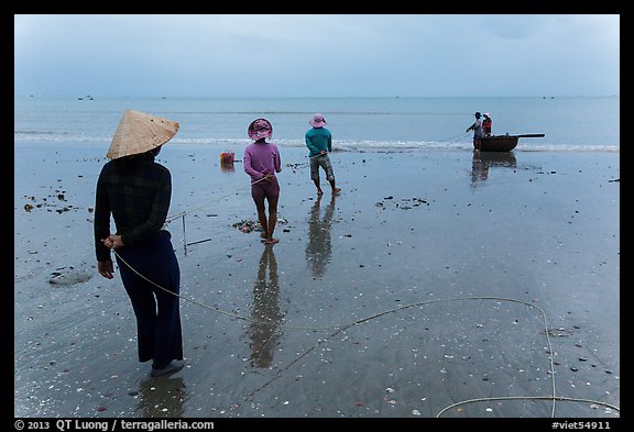 Fishermen pulling line onto beach. Mui Ne, Vietnam