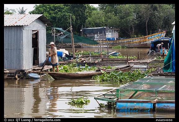 Man paddling out of houseboat. My Tho, Vietnam