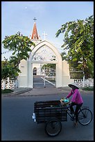 Woman bicycling in front of church. Tra Vinh, Vietnam ( color)