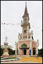 Man drying rice hulls in front of church. Tra Vinh, Vietnam (color)