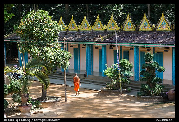 Monk walking past huts, Hang Pagoda. Tra Vinh, Vietnam (color)