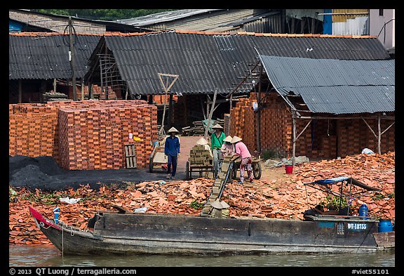 Workers loading bricks on boat. Sa Dec, Vietnam