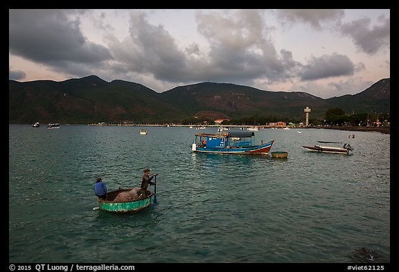 Men in coracle boat paddling in Con Son harbor. Con Dao Islands, Vietnam (color)