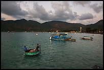 Men in coracle boat paddling in Con Son harbor. Con Dao Islands, Vietnam ( color)