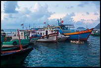 Fishing boats and man standing on raft, early morning, Con Son harbor. Con Dao Islands, Vietnam ( color)