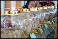 Woman peering over row of eddible birds nest jars. Con Dao Islands, Vietnam ( color)