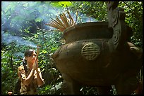 Tourist praying at an urn with incense near the entrance of Phong Nha Cave. Vietnam (color)