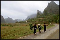Villagers walking down the road with limestone peaks in the background, Ma Phuoc Pass area. Northeast Vietnam