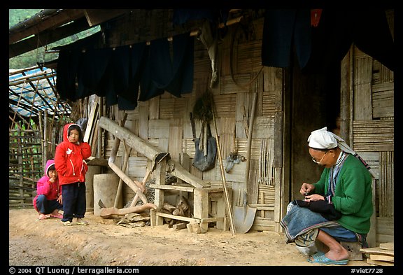 Elderly woman sewing  on her doorstep as kids look up. Northeast Vietnam (color)