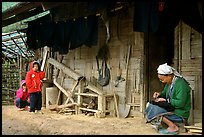 Elderly woman sewing  on her doorstep as kids look up. Northeast Vietnam