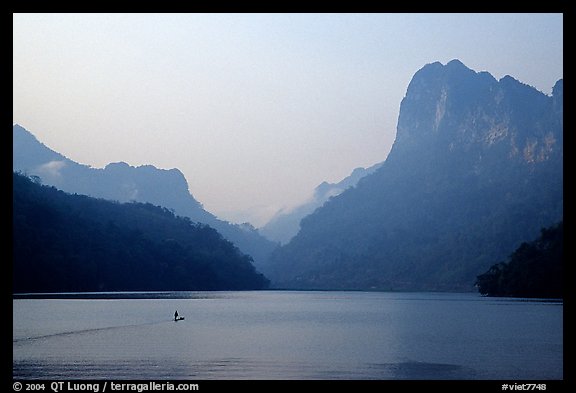 Dugout boat in Ba Be Lake, surrounded by tall cliffs, early morning. Northeast Vietnam