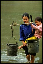 Woman of the Tay minority carrying crossing the river with child, Ba Be Lake. Vietnam